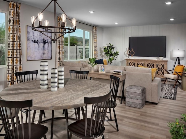 dining area with an inviting chandelier, wooden walls, and light hardwood / wood-style floors