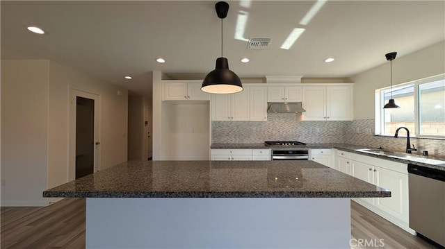 kitchen featuring appliances with stainless steel finishes, decorative light fixtures, a center island, and white cabinets