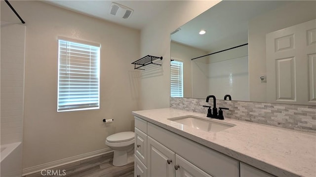 full bathroom featuring vanity, hardwood / wood-style floors, decorative backsplash, and a wealth of natural light