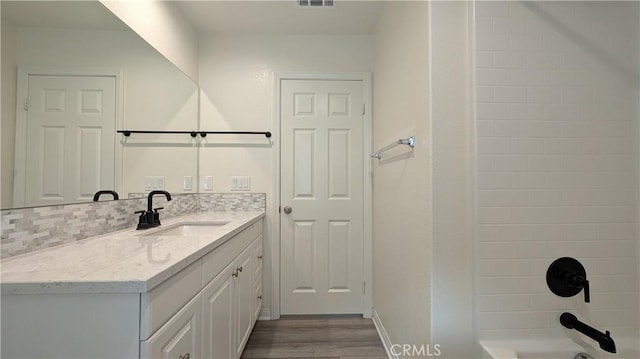 bathroom featuring tasteful backsplash, vanity, shower / washtub combination, and hardwood / wood-style floors