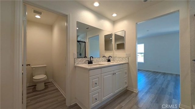 bathroom with wood-type flooring, toilet, vanity, and decorative backsplash