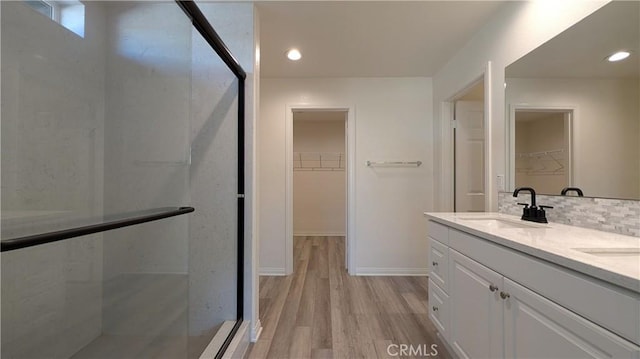 bathroom with tasteful backsplash, vanity, a shower with shower door, and hardwood / wood-style flooring