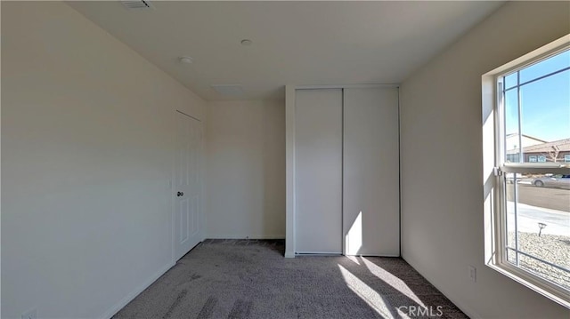 unfurnished bedroom featuring a closet, carpet floors, and multiple windows