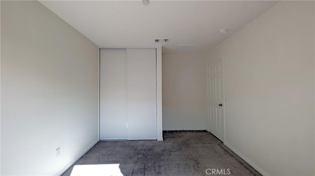 unfurnished bedroom with dark carpet and a closet