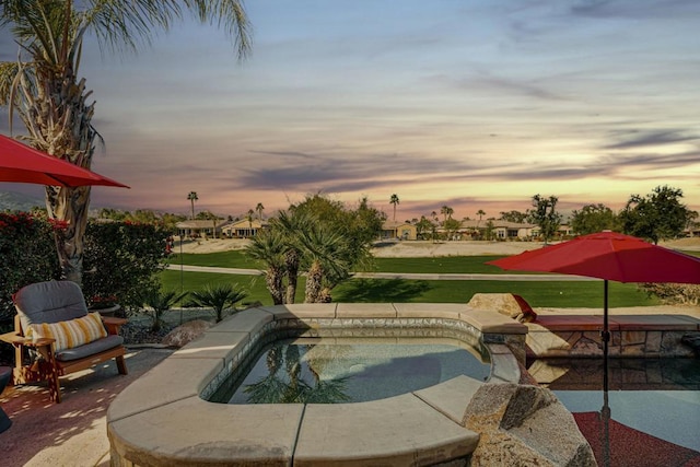 pool at dusk with a yard and a patio area