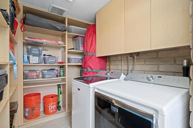 clothes washing area with washing machine and clothes dryer and light tile patterned floors