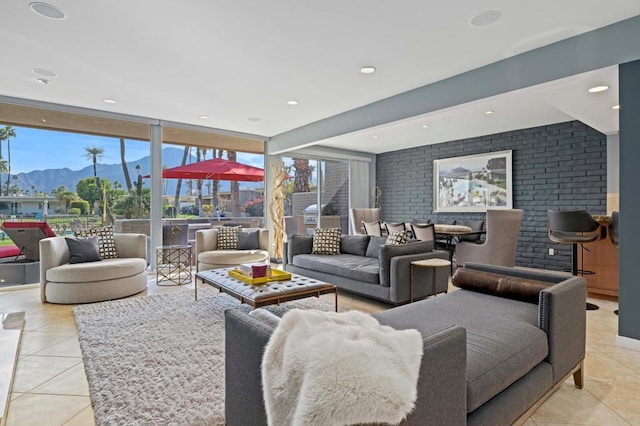 living room with brick wall, floor to ceiling windows, a mountain view, and light tile patterned floors