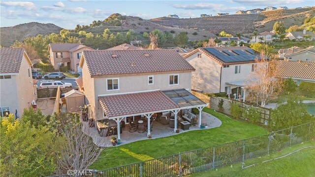 rear view of house featuring a yard, a mountain view, and a patio area