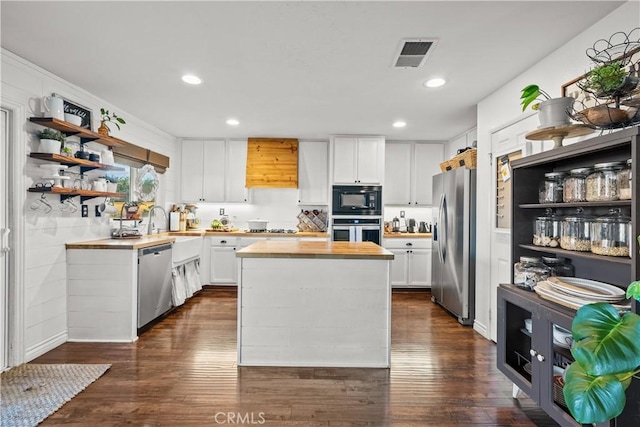 kitchen with appliances with stainless steel finishes, white cabinets, wooden counters, and visible vents