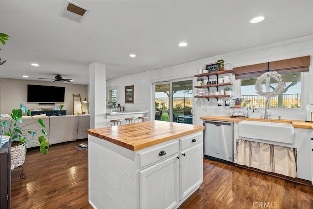 kitchen with a sink, visible vents, white cabinets, wooden counters, and stainless steel dishwasher