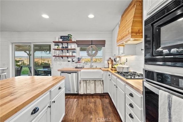 kitchen with a sink, white cabinets, stainless steel appliances, and wooden counters