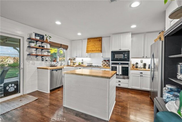 kitchen featuring wood counters, stainless steel appliances, a center island, and white cabinets