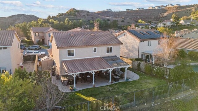 back of house featuring a mountain view, a lawn, and a patio