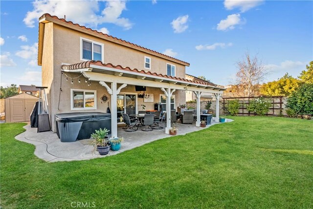 back of property with a hot tub, a shed, a patio area, and a lawn