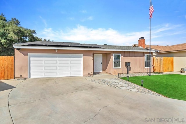 single story home with a garage, a front yard, and solar panels