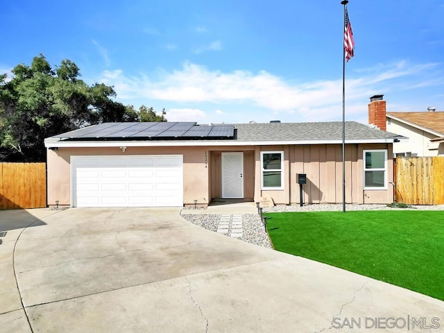 ranch-style house with a garage, a front yard, and solar panels