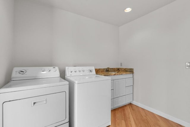 laundry room with cabinets, sink, light hardwood / wood-style flooring, and independent washer and dryer