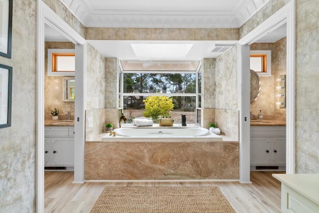 bathroom with ornamental molding, vanity, a skylight, and hardwood / wood-style floors