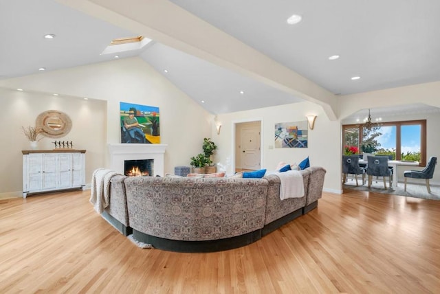 living room with a notable chandelier, vaulted ceiling, and light wood-type flooring