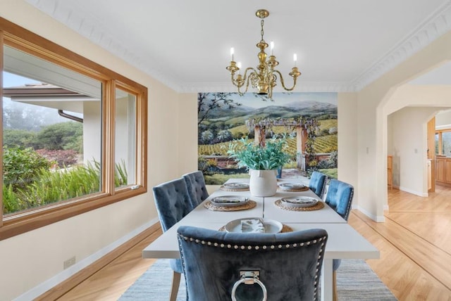 dining room with ornamental molding, a wealth of natural light, a notable chandelier, and light hardwood / wood-style flooring