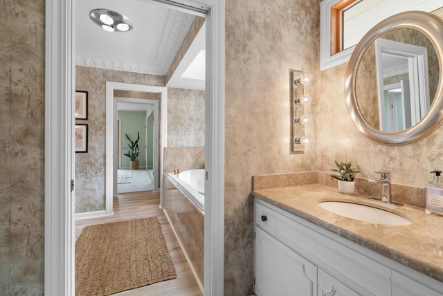 bathroom featuring wood-type flooring, tiled bath, vanity, and crown molding