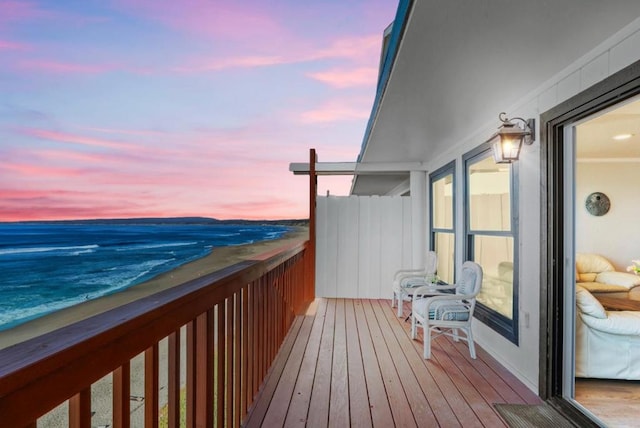 balcony at dusk with a water view and a beach view