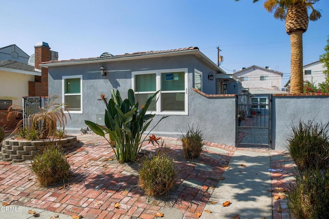 bungalow-style house featuring a gate, fence, and stucco siding