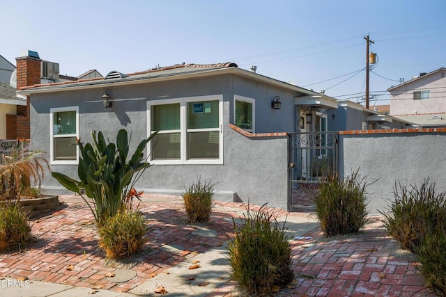 view of front of property featuring a gate, fence, and stucco siding