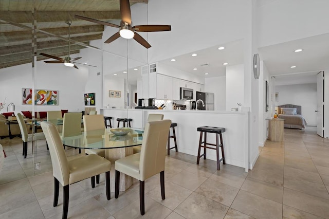 dining area featuring beam ceiling, high vaulted ceiling, and ceiling fan