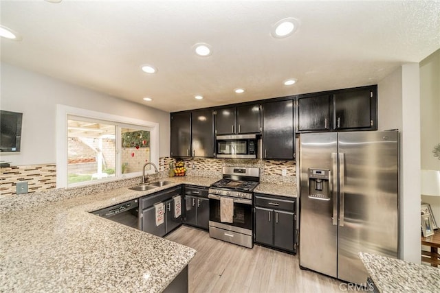 kitchen featuring stainless steel appliances, light stone countertops, sink, and light wood-type flooring