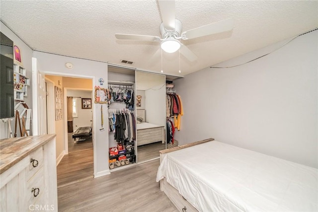 bedroom with ceiling fan, a textured ceiling, pool table, a closet, and light wood-type flooring