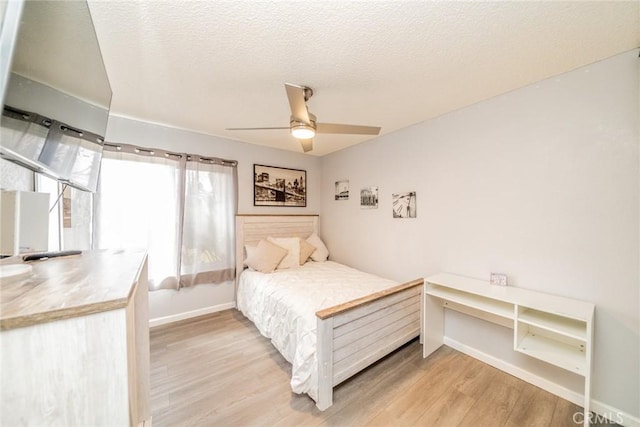 bedroom featuring a textured ceiling, ceiling fan, and light wood-type flooring