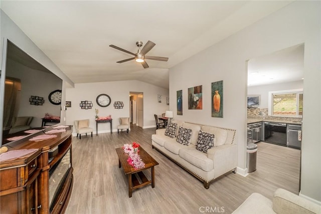 living room with vaulted ceiling, ceiling fan, and light wood-type flooring