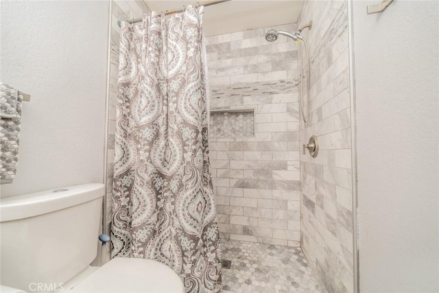 bathroom featuring toilet and curtained shower