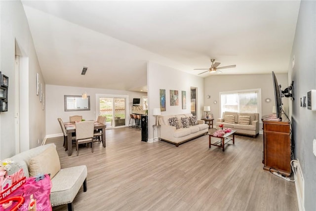 living room featuring vaulted ceiling, light hardwood / wood-style floors, and ceiling fan