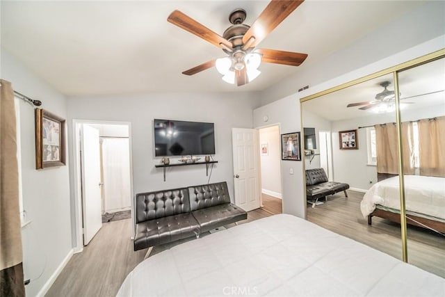 bedroom featuring lofted ceiling, light hardwood / wood-style floors, a closet, and ceiling fan