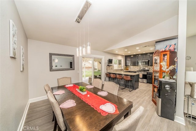 dining area with vaulted ceiling and light wood-type flooring