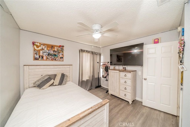 bedroom with ceiling fan, light hardwood / wood-style floors, and a textured ceiling