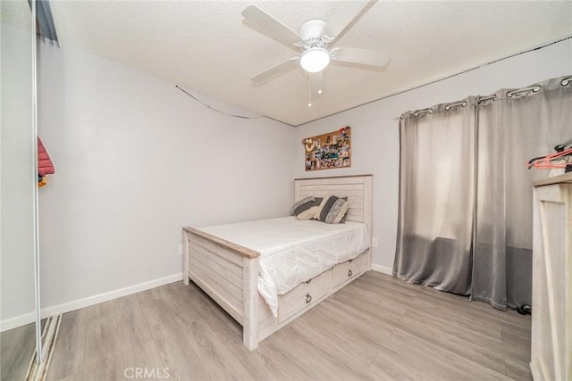 bedroom with a textured ceiling, light hardwood / wood-style floors, and ceiling fan