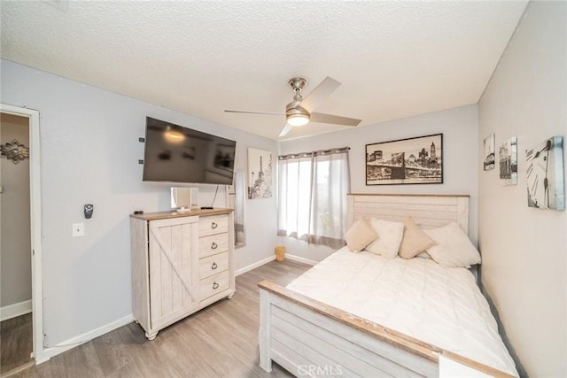 bedroom with a textured ceiling, ceiling fan, and light wood-type flooring