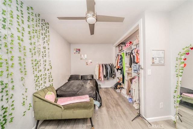 bedroom with light wood-type flooring, ceiling fan, and a closet