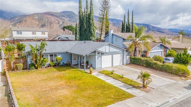 view of front of property with a garage, a mountain view, and a front lawn