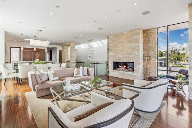 living room with a fireplace, wood-type flooring, and expansive windows