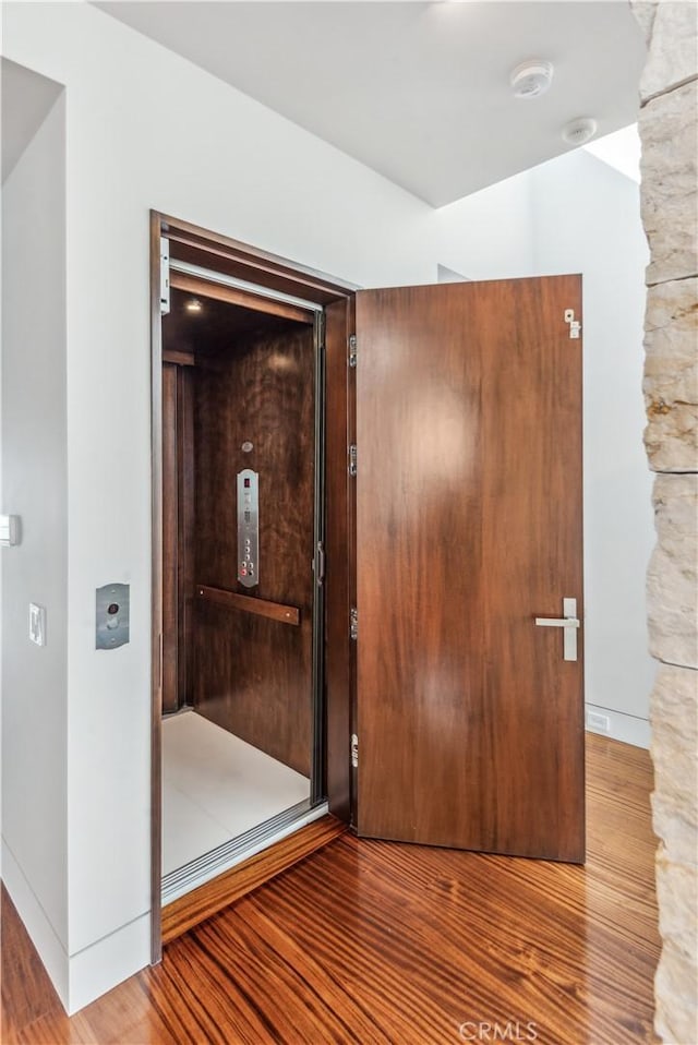 corridor with hardwood / wood-style flooring