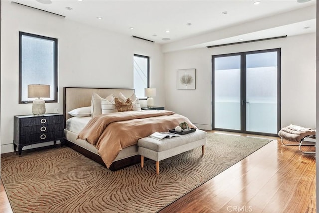 bedroom featuring light hardwood / wood-style floors, multiple windows, and access to outside