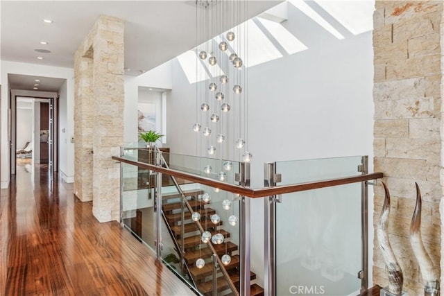 stairs featuring ornate columns, wood-type flooring, and a skylight