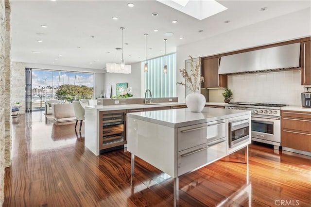 kitchen with wine cooler, sink, a center island, ventilation hood, and appliances with stainless steel finishes