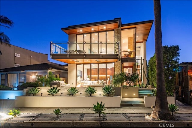 back house at twilight with a balcony