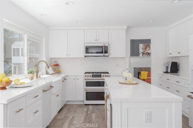 kitchen featuring white cabinetry, white appliances, a kitchen island, and light wood-type flooring