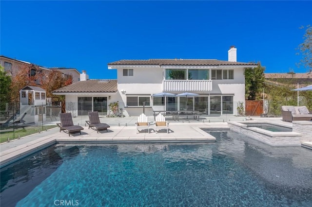 back of house with a swimming pool with hot tub and a patio area